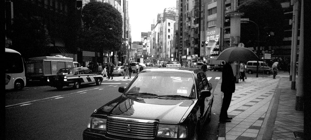 Taxi und Mann mit Regenschirm in Downtown Tokyo.